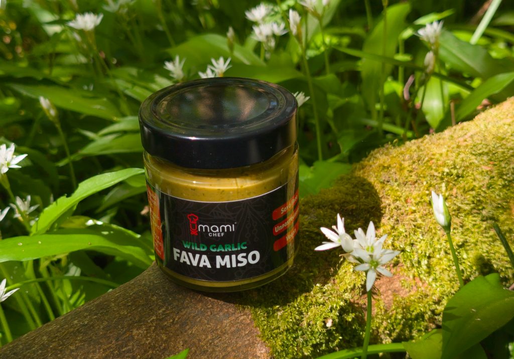 Jar of wild garlic miso surrounded by the wild garlic used to create it