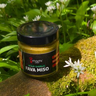 Jar of wild garlic miso surrounded by the wild garlic used to create it